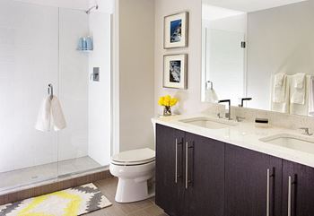 Spa baths with frameless glass shower, beautiful ebony vanity with dual sinks, large mirrors and hard surface flooring